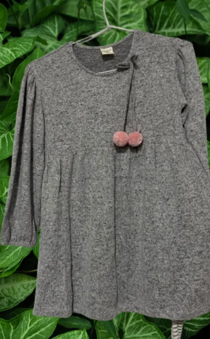 Vestido gris de manga larga con detalle de pompones en el pecho.lanilla super suave y calentita. Ideal para un look casual y cómodo.