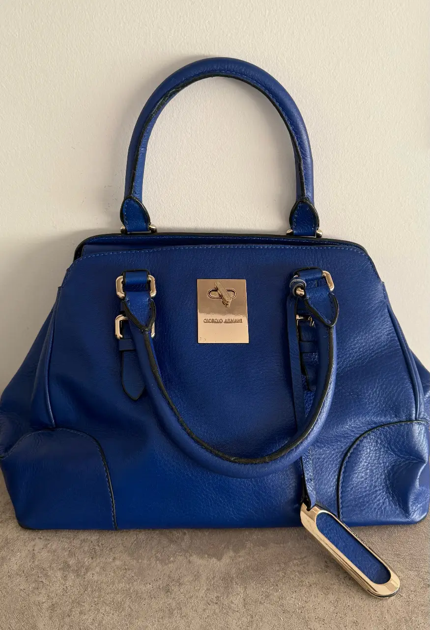 Cartera Giorgio Armani de cuero azul, con manijas y detalles dorados. Ideal para llevar tus esenciales con estilo.gran capacidad. división interior con cierre 