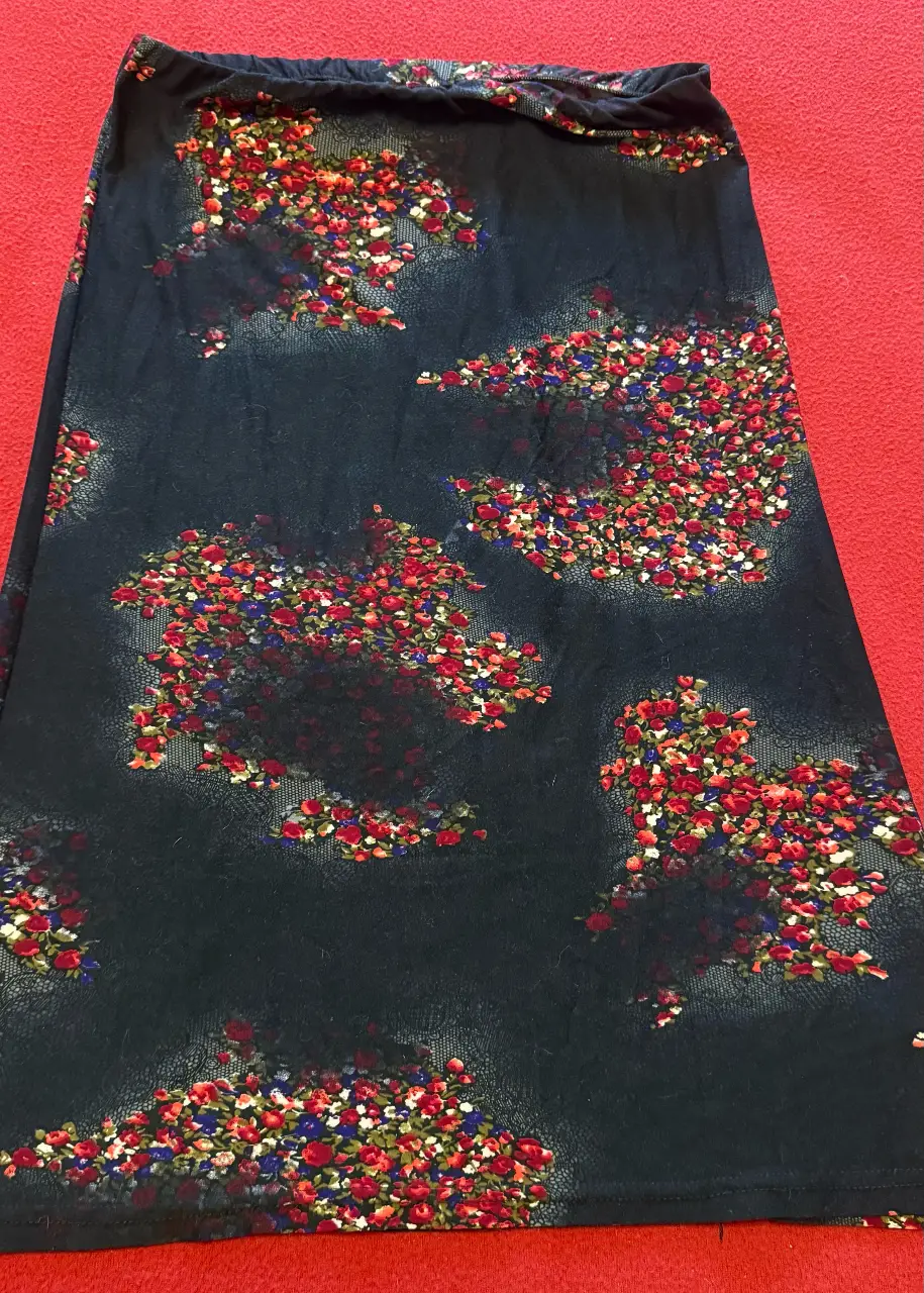 Pollera recta de mujer con estampado floral en tonos rojos y blancos sobre fondo negro. Talle M. Ideal para un look casual y fresco.