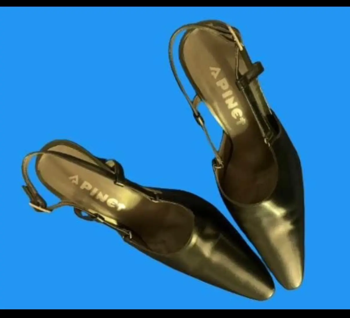 Elegantes zapatos stilettos con talón abierto color peltre.  Confeccionados en cuero. presentan un diseño de punta fina y tiras delicadas que aseguran un ajuste perfecto. La marca APINET se destaca en la plantilla, añadiendo un toque de sofisticación.