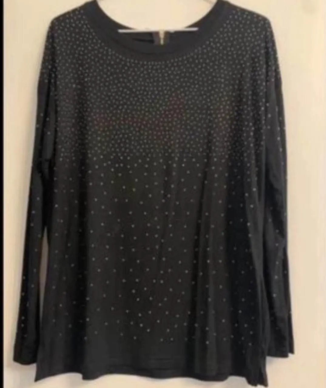 Remera manga larga negra con detalles de mini tachas. Cuello redondo con cierre en la parte superior. Ideal para un look casual con un toque de brillo.suelta modal