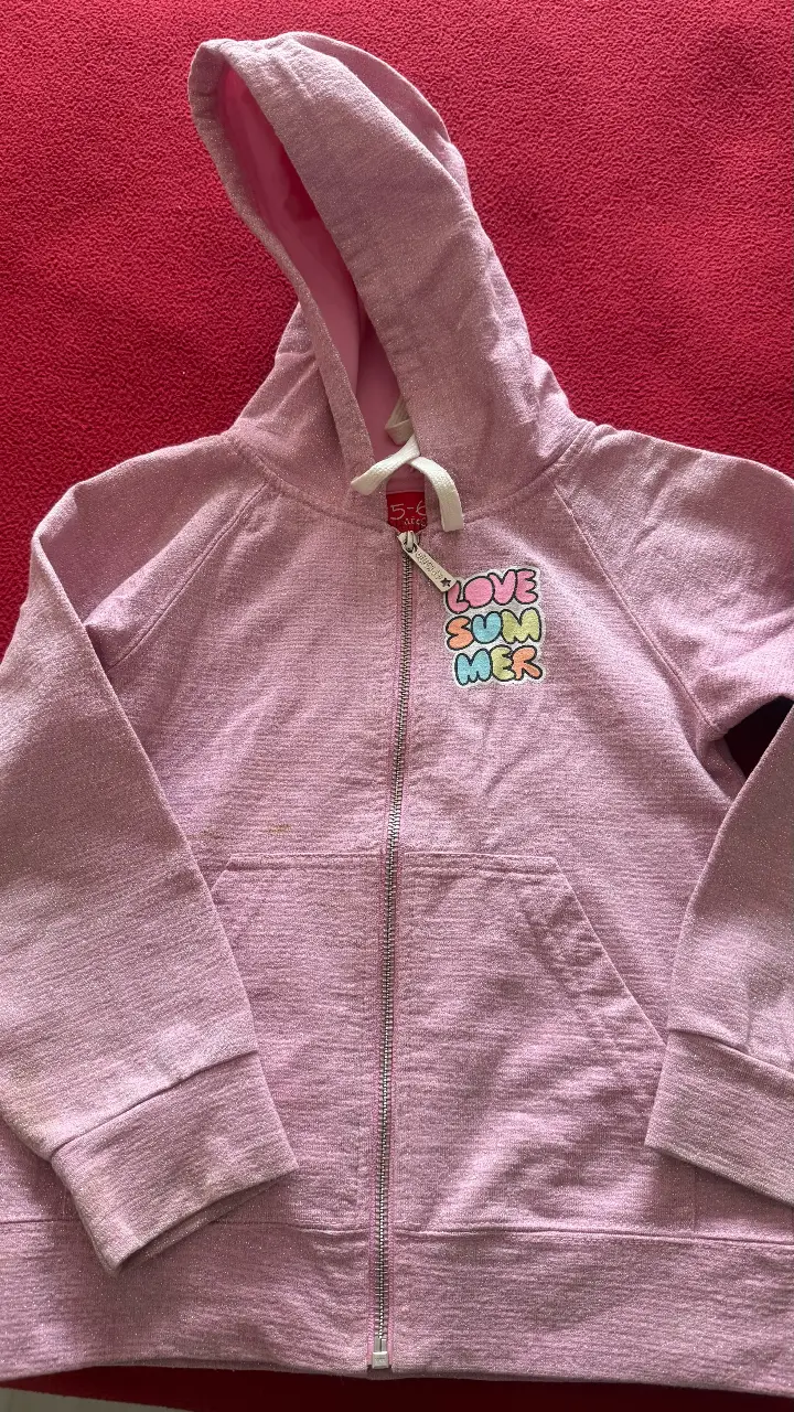 Buzo con cierre para niña, color rosa Lurex. Tiene capucha y un bolsillo delantero. En el frente, un estampado con la frase 'LOVE SUMMER'. Ideal para un look casual y cómodo.super rebajado