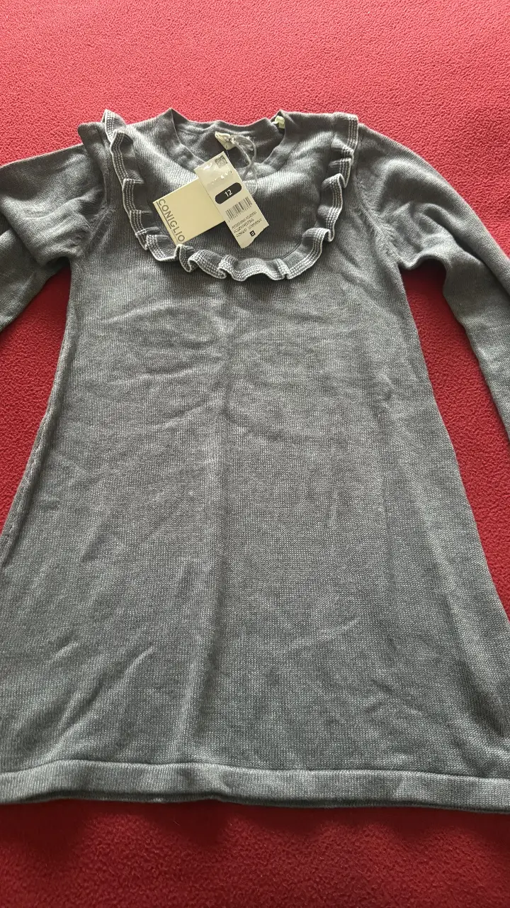 Vestido gris de niña, con cuello redondo y detalle de volados en el cuello. Manga larga. Talle 12.