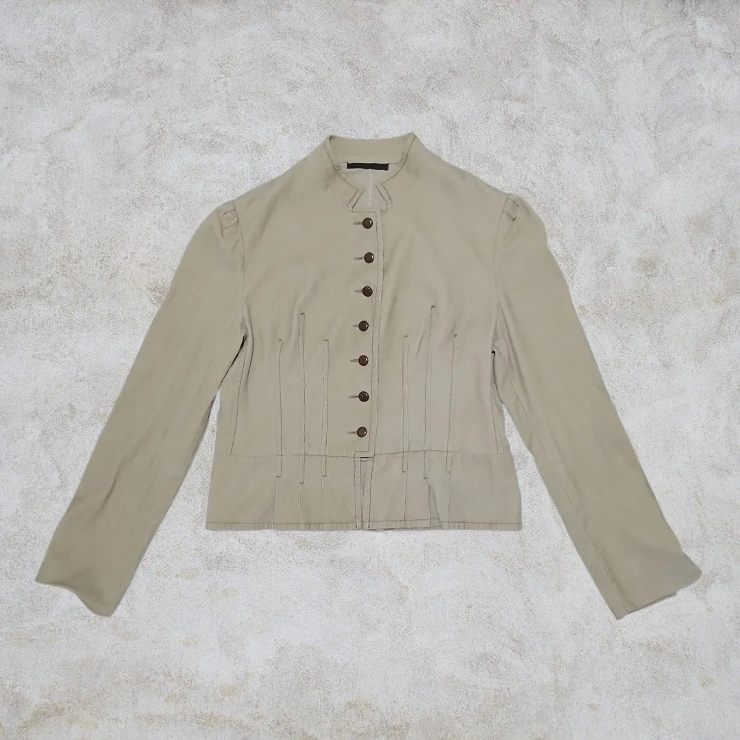 Chaqueta de mujer color crudo con cuello alto y botones. Diseño entallado con detalles de costura y frunces en la cintura. Ideal para un look elegante y sofisticado.

Talle S/M
la tela es un corderoy liviano