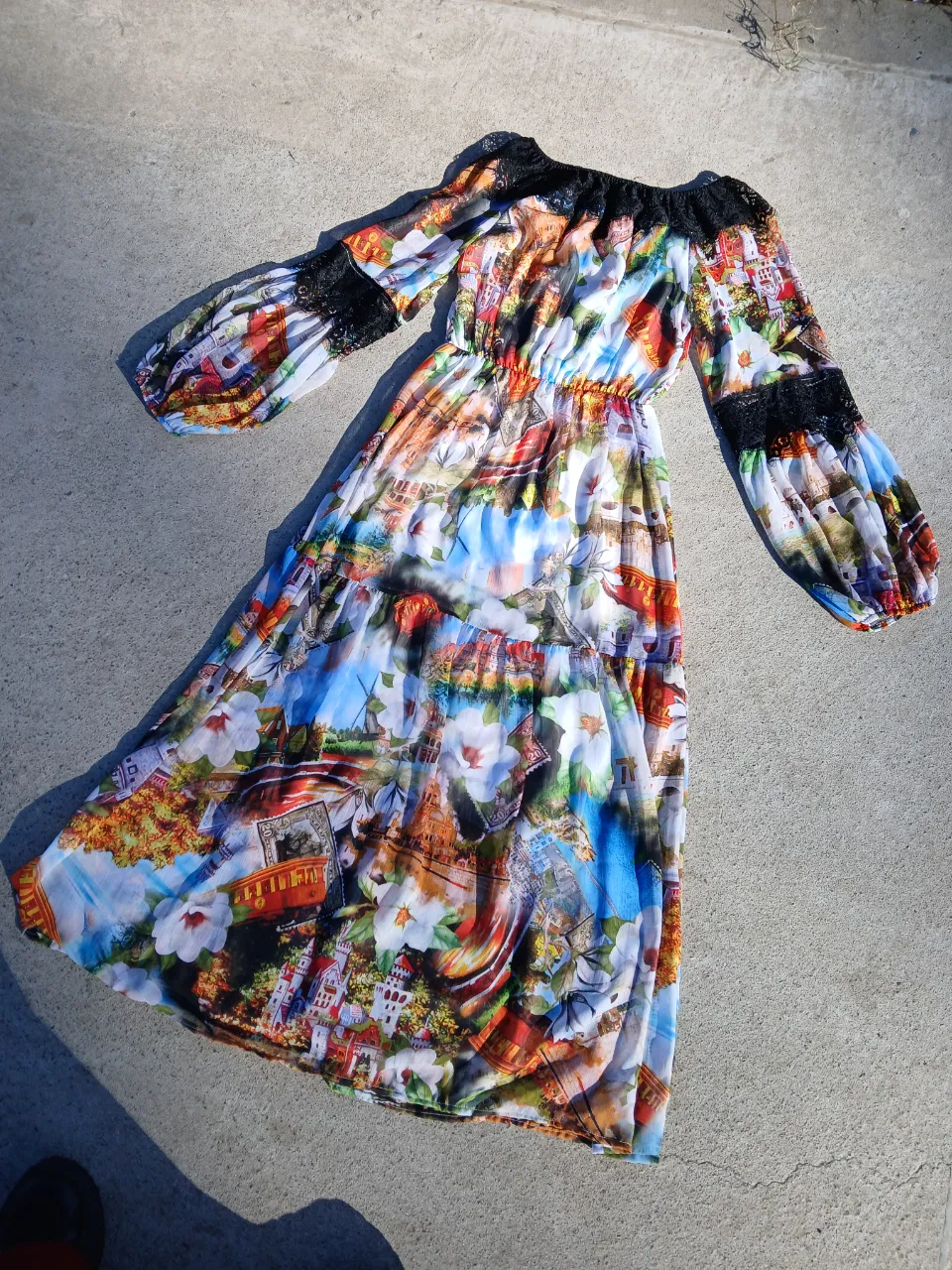 Vestido largo de gasa con estampado de paisajes y flores. Mangas largas con detalles de encaje negro. Cintura elastizada. Ideal para un look bohemio y fresco.
Talle L
Tiene forro
Es italiano 
