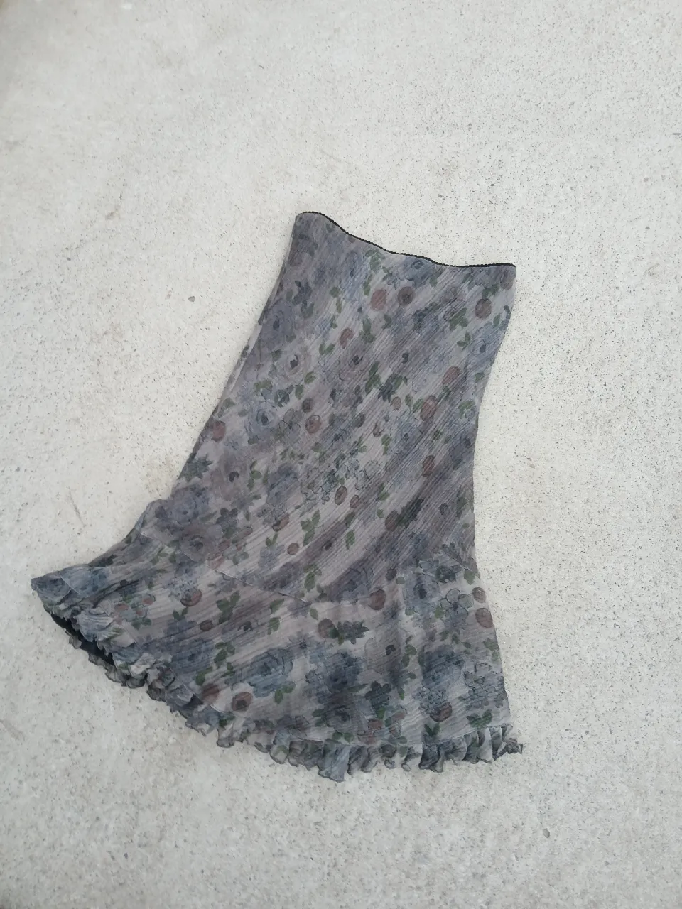 Pollera larga de gasa con estampado floral en tonos grises y azules. Tiene volados en el borde y forro interior. Talle 44.