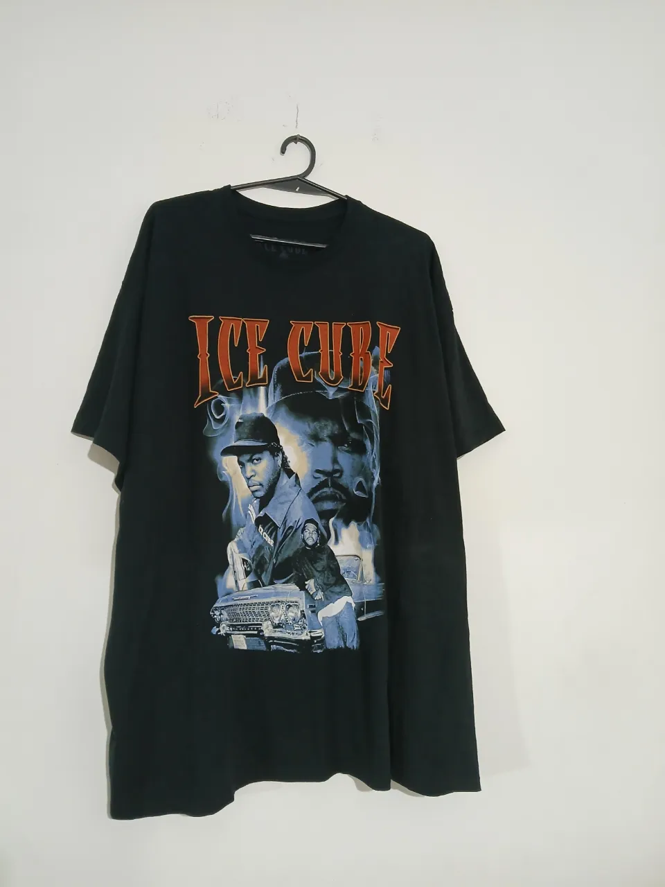 Remera negra de Ice Cube con estampado vintage. Diseño con imágenes del rapero y el logo "Ice Cube" en naranja. Ideal para looks urbanos y fanáticos del hip hop.
