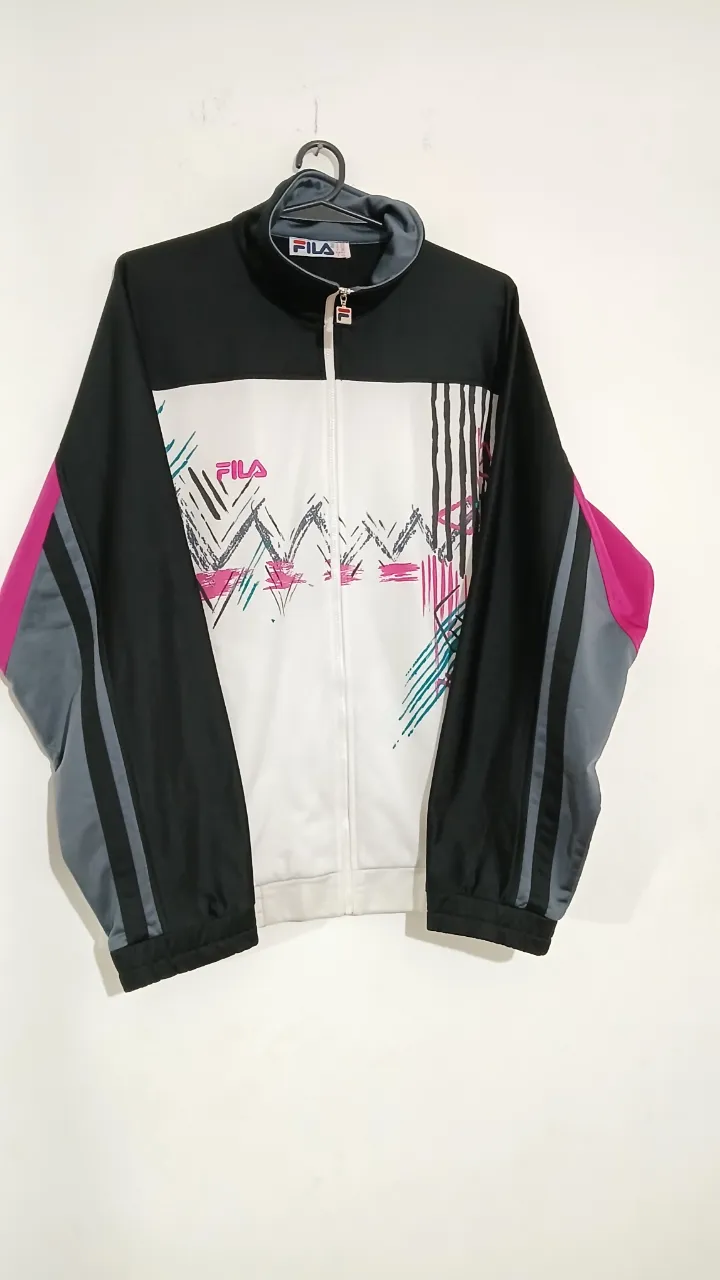 Campera deportiva Fila vintage con cierre, diseño retro con detalles en rosa y gris. Ideal para un look urbano y cómodo.
Talle L