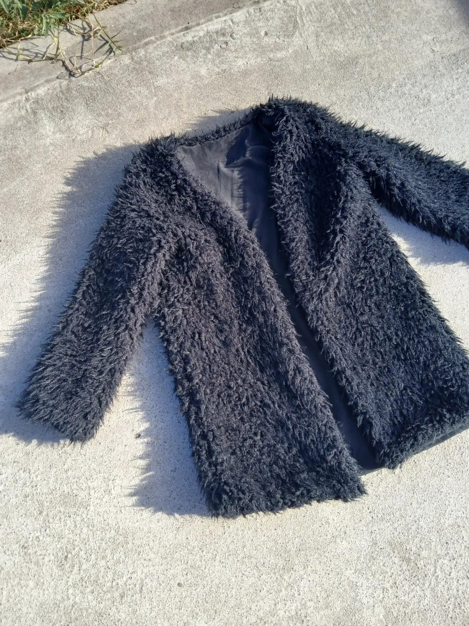 Abrigo de mujer negro con textura de peluche. Ideal para un look moderno y abrigado. Perfecto para usar en salidas o eventos.