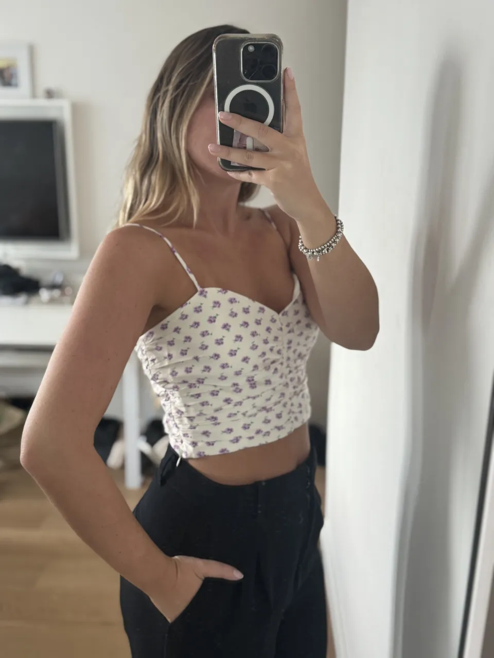 Top blanco con estampado floral de flores lilas y detalles en verde. Breteles finos y fruncido en el frente.