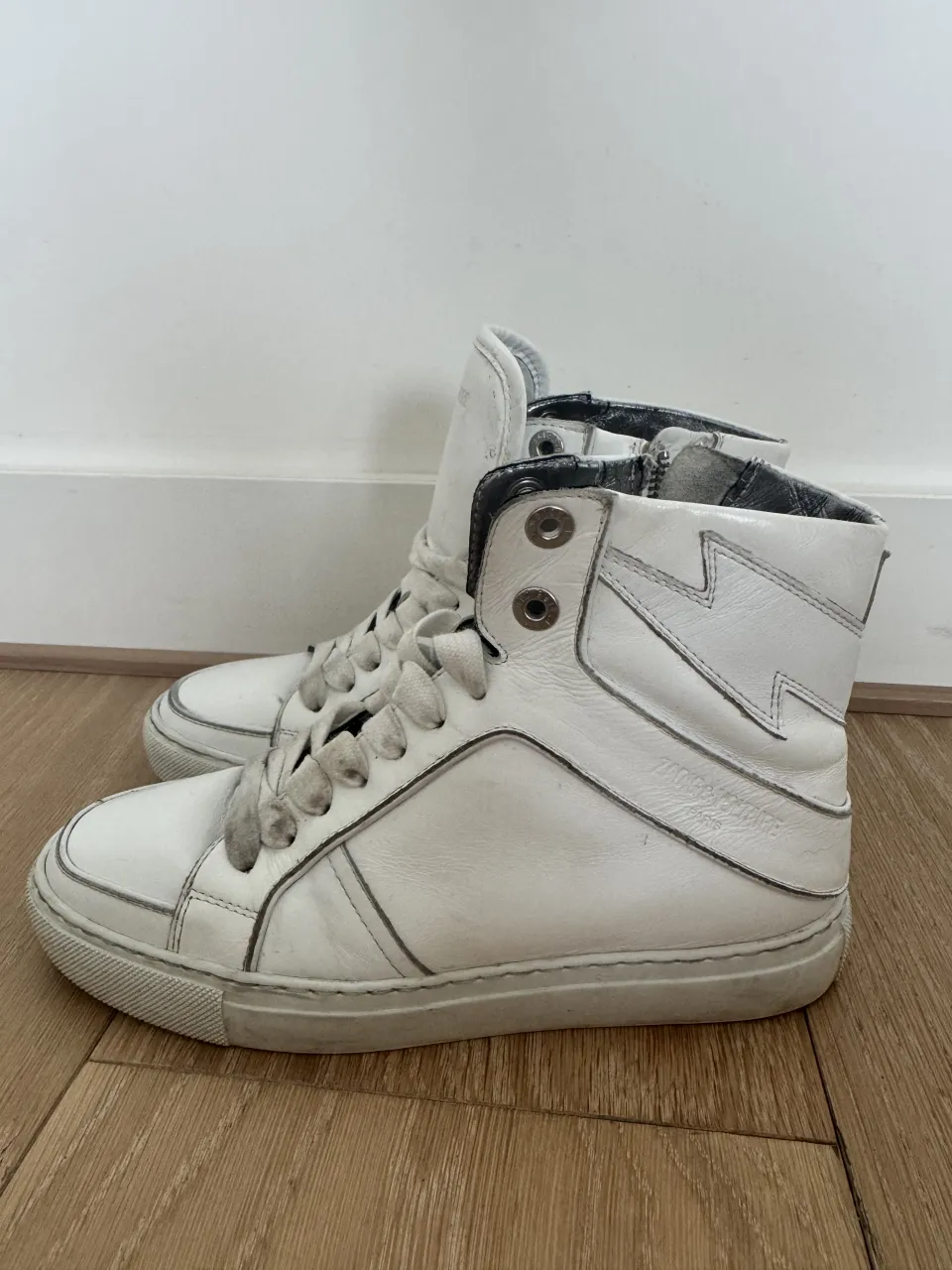 Zapatillas de cuero blancas con detalles en gris y cierre lateral.