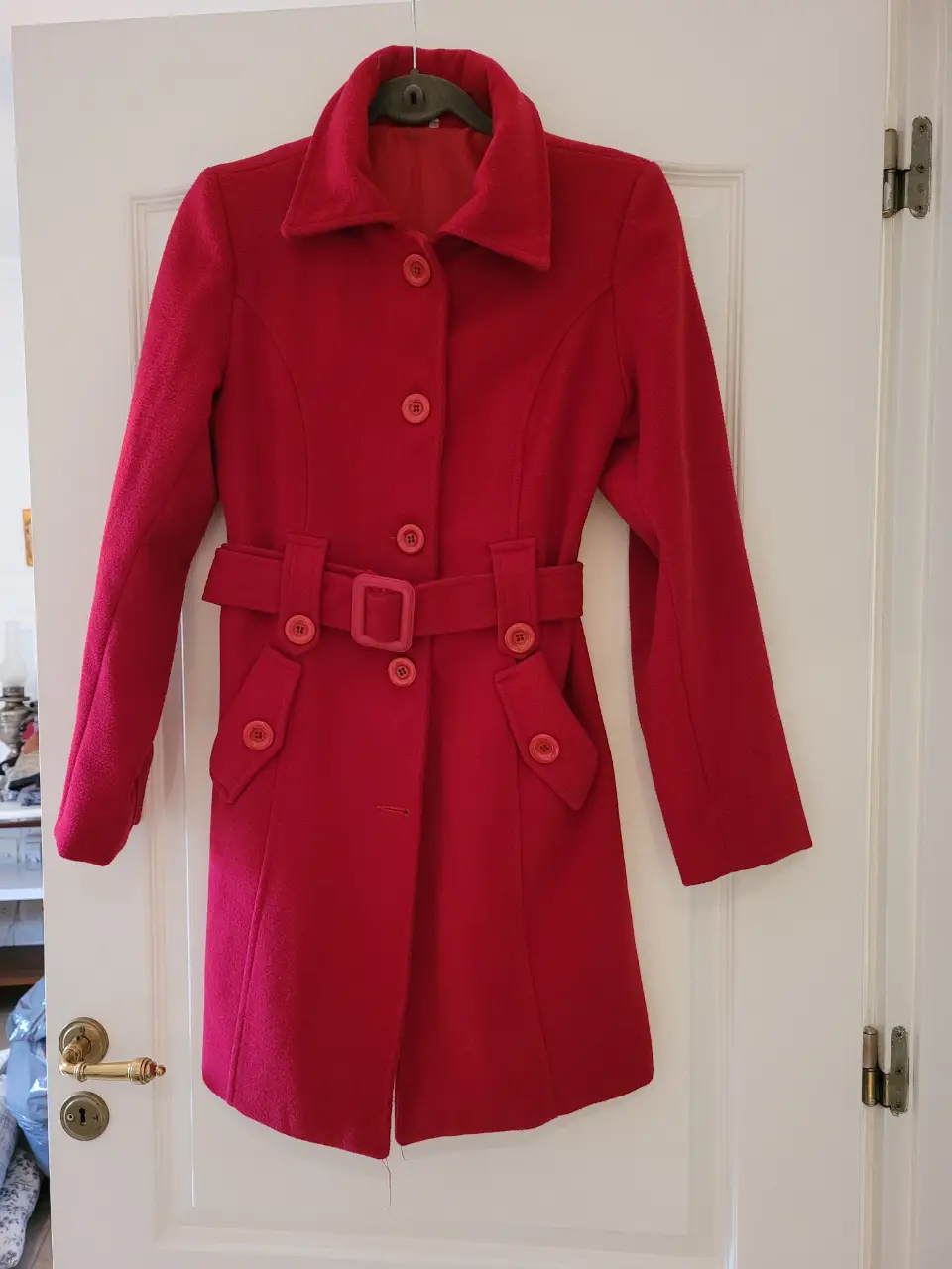 Sobretodo rojo de paño con cinturón. Corte entallado, ideal para el invierno. Posee botones y bolsillos. El color es más apagado de lo que se ve en la foto. 