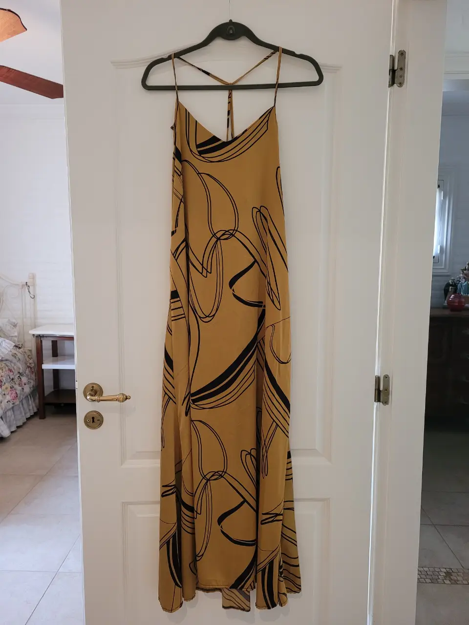 Vestido largo de mujer, color amarillo/dorado con estampado negro. Diseño con tirantes finos y espalda descubierta. Ideal para eventos de verano.