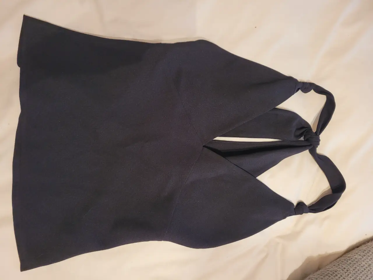 Top negro con escote pronunciado  y detalle de nudo en la espalda. Ideal para un look elegante y moderno.