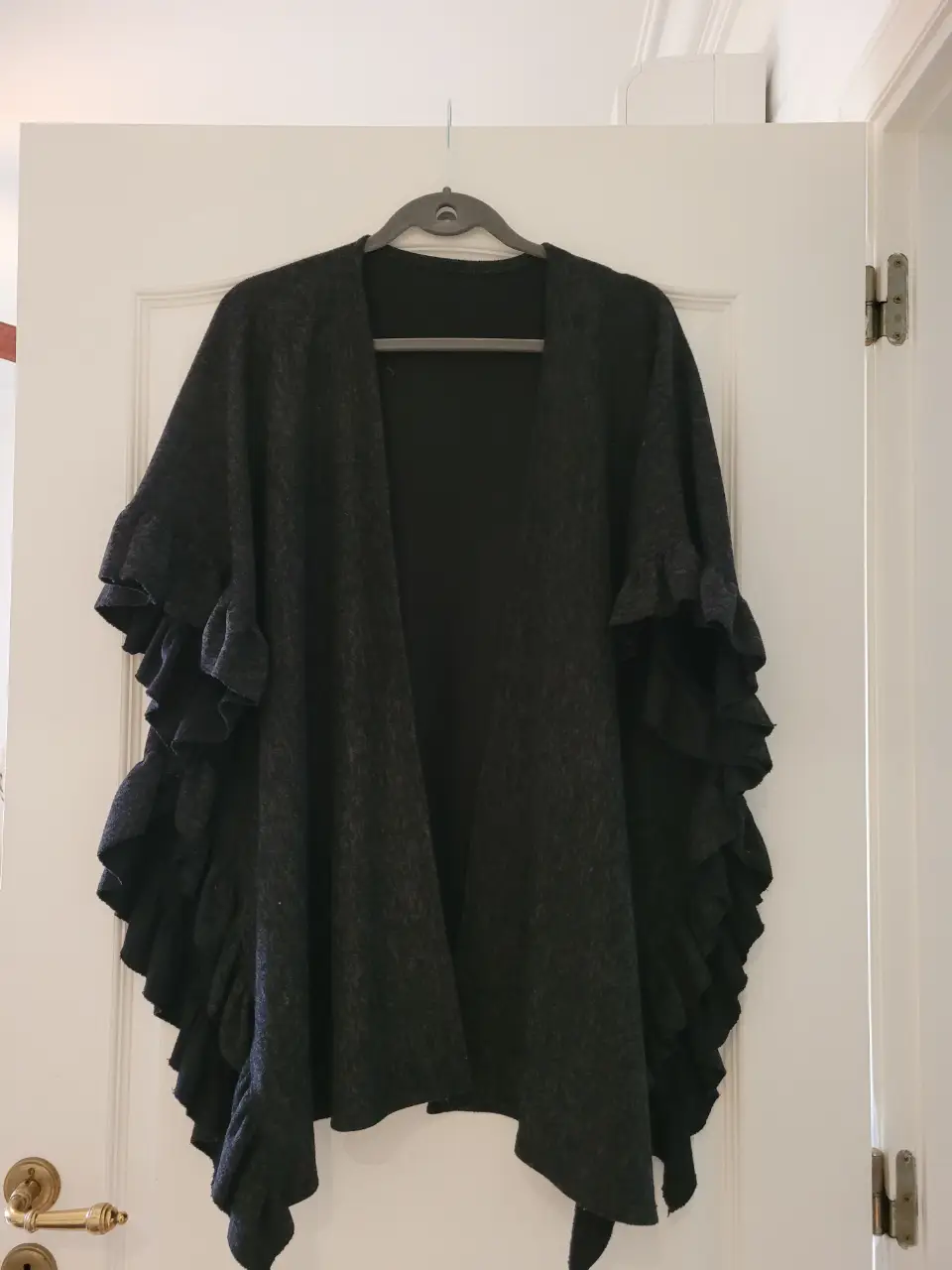 Poncho gris oscuro con volados en los bordes, ideal para un look elegante y sofisticado. Perfecto para combinar con diferentes outfits.