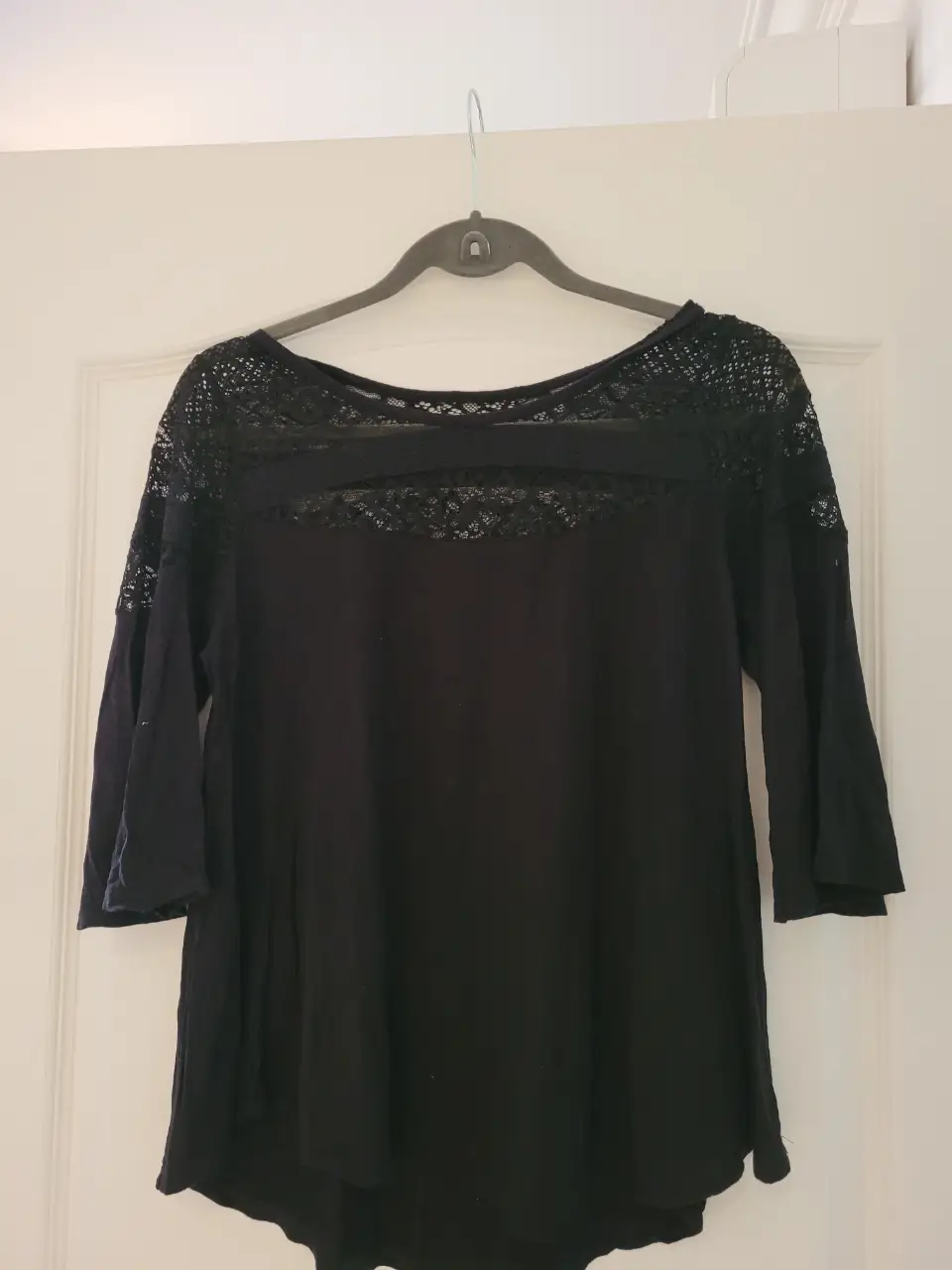 Remera negra con detalles de encaje en la parte superior y mangas 3/4. Ideal para un look elegante y sofisticado.