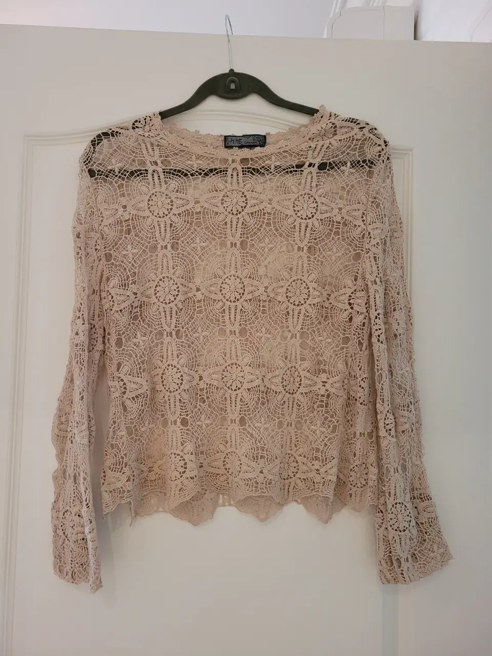 Blusa de encaje color crudo, con mangas largas y detalles florales. Ideal para un look bohemio y elegante.