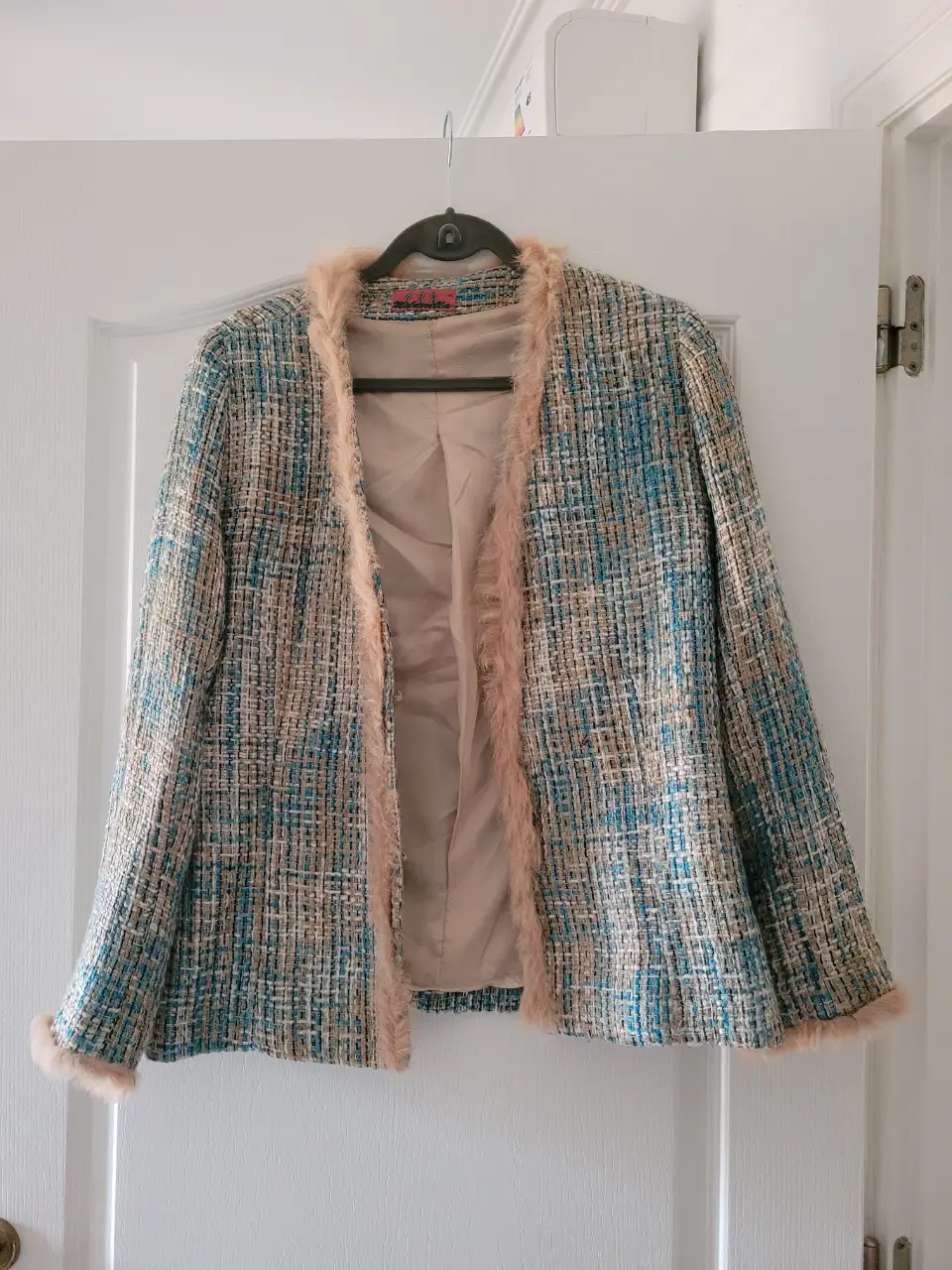 Elegante blazer de tweed con detalles de piel sintética en el cuello y puños. Ideal para un look sofisticado y abrigado.