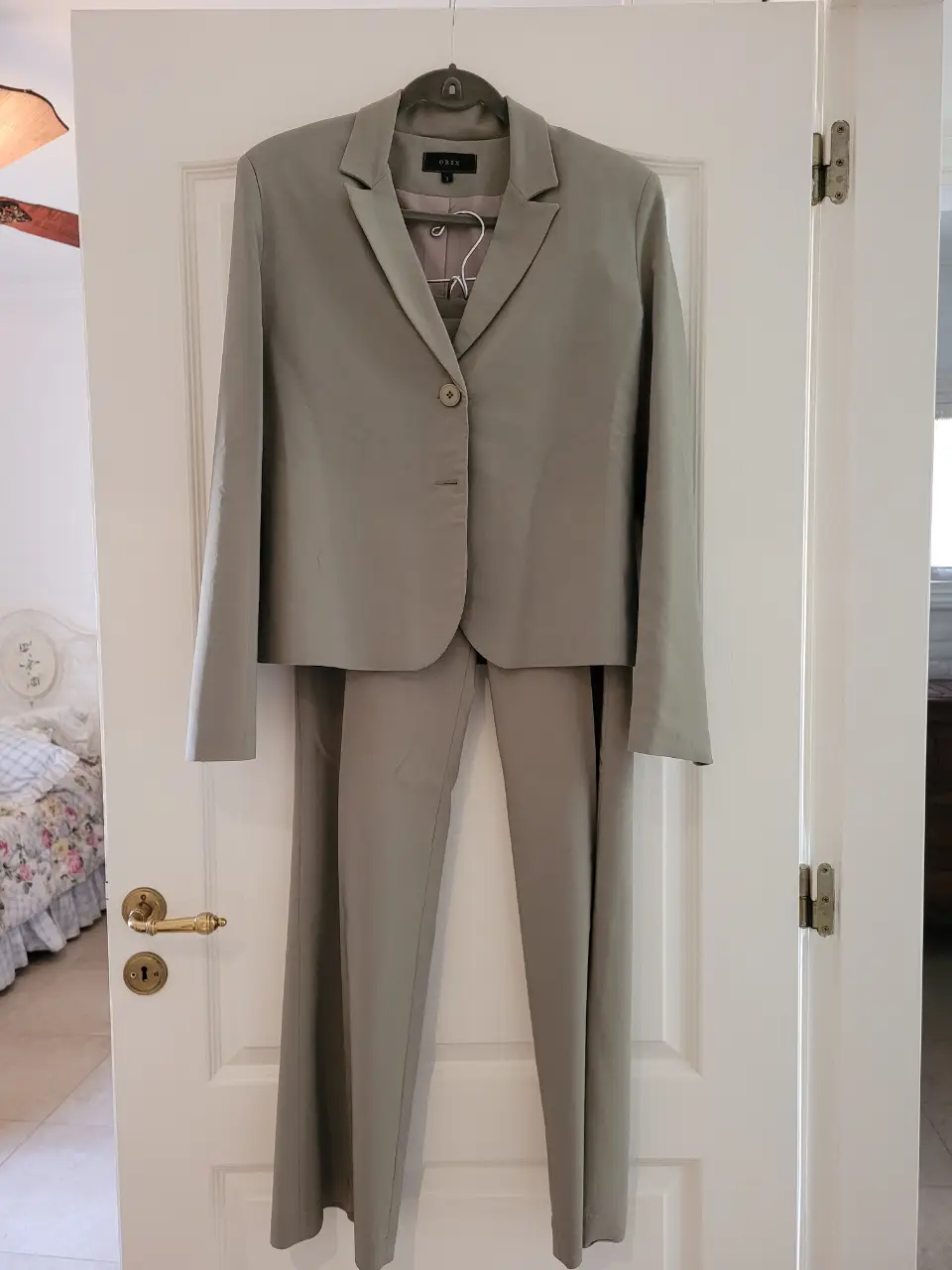 Conjunto de pantalón sastrero de mujer, color gris verdoso con corte recto, tiro medio y dos botones en la cintura. Y blazer con botones y escote V.  Ideal para un look formal o de oficina. 