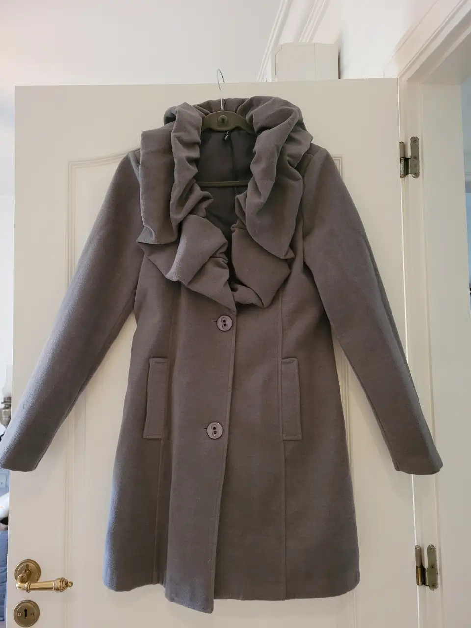 Tapado gris de paño con cuello voluminoso y botones. Ideal para el invierno, este abrigo combina estilo y abrigo.