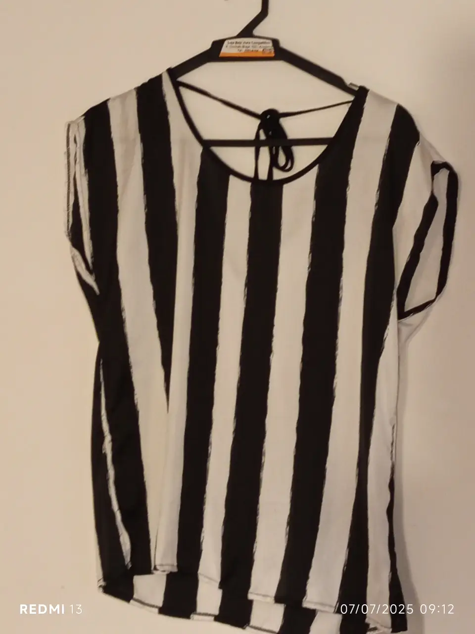 Blusa seda  a rayas verticales en blanco y negro, con cuello redondo y detalle de lazo en la espalda. Ideal para un look casual y moderno.