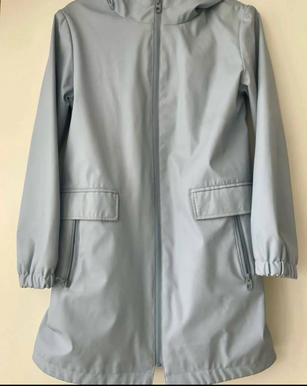 Impermeable celeste de la marca Zara Basic, con capucha, bolsillos con cierre y cierre frontal. Ideal para protegerte de la lluvia con estilo. (tipo engomado )