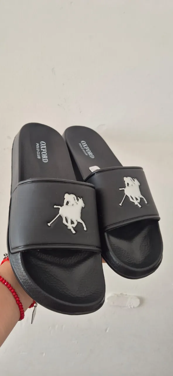 Ojotas negras de la marca Oxford Polo Club, ideales para el verano o para estar cómodo en casa. Tienen un diseño moderno con el logo de la marca en blanco.