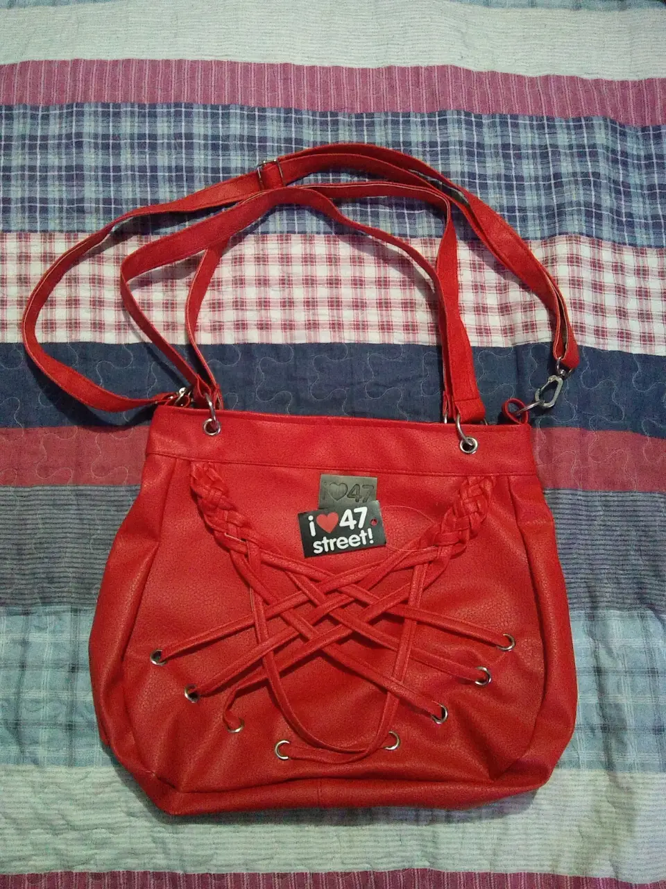 Cartera roja de hombro con detalles trenzados y cierre. Ideal para un look casual y moderno. Marca 'i 47 street'.