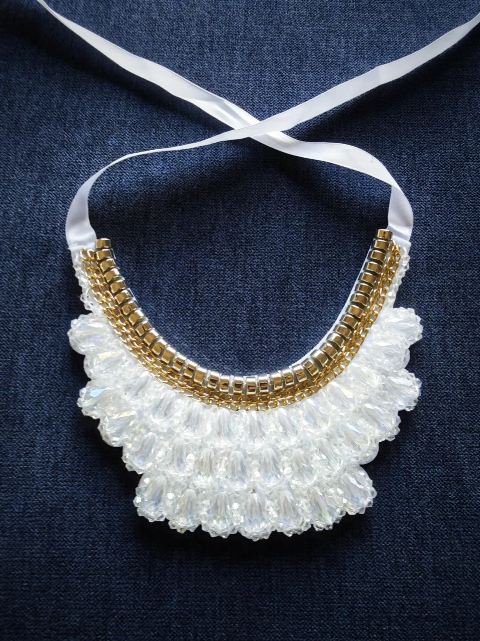 Collar artesanal con base blanca y detalles dorados. Ideal para eventos especiales o para darle un toque elegante a cualquier look.