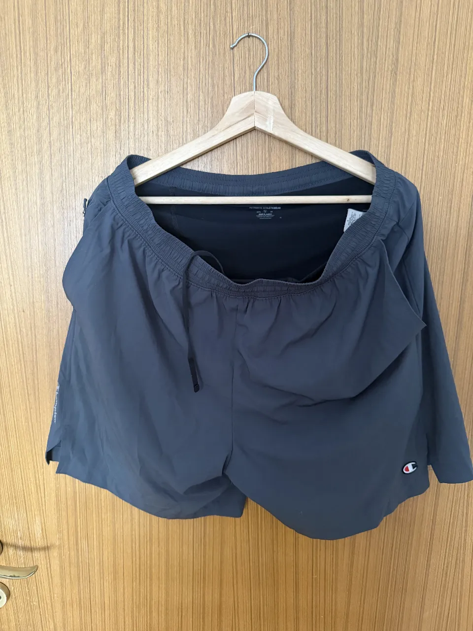 Shorts deportivos con calzas grises de Champion, ideales para entrenar o para un look casual y cómodo. Cuentan con bolsillos laterales y un diseño moderno.