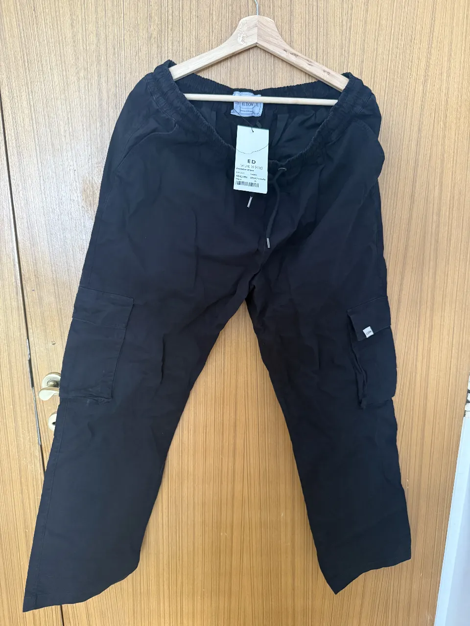 Pantalón cargo negro de corte recto, con cintura elastizada y cordón de ajuste. Posee bolsillos laterales y en los laterales de las piernas. Ideal para un look casual y cómodo.