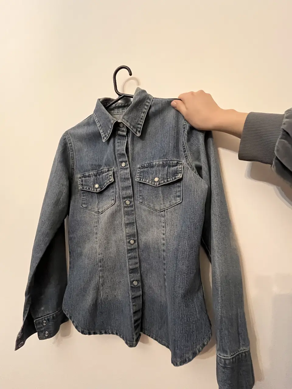 Camisa de jean azul, con dos bolsillos delanteros y botones. Ideal para un look casual y versátil.