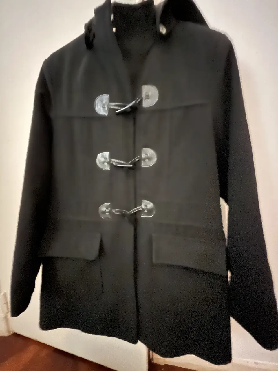 Tapado negro con capucha y broches de cierre. Ideal para el invierno, estilo clásico y versátil. Montgonery con capucha desmontable.