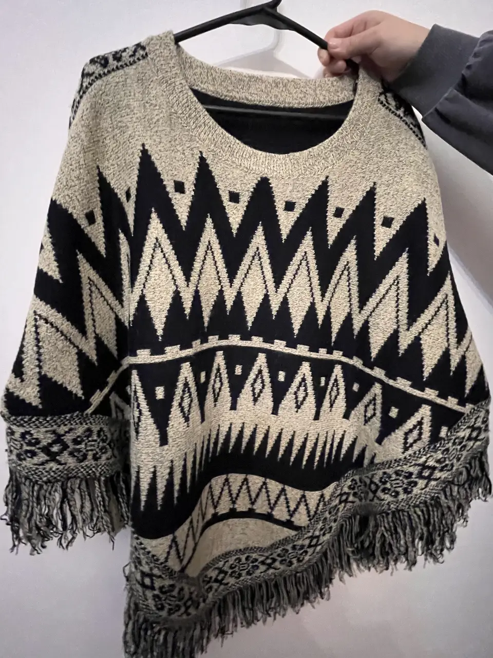 Poncho tejido con diseño geométrico en blanco y negro, con flecos en el borde. Ideal para un look bohemio y abrigado.