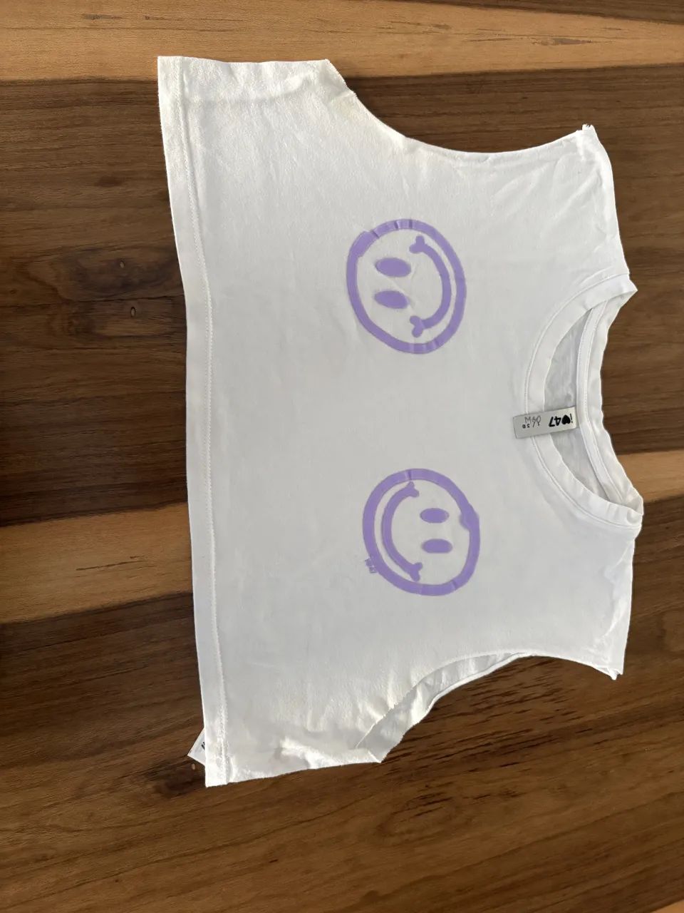 Remera blanca crop con estampa de caritas sonrientes en color lila. Ideal para un look casual y divertido.