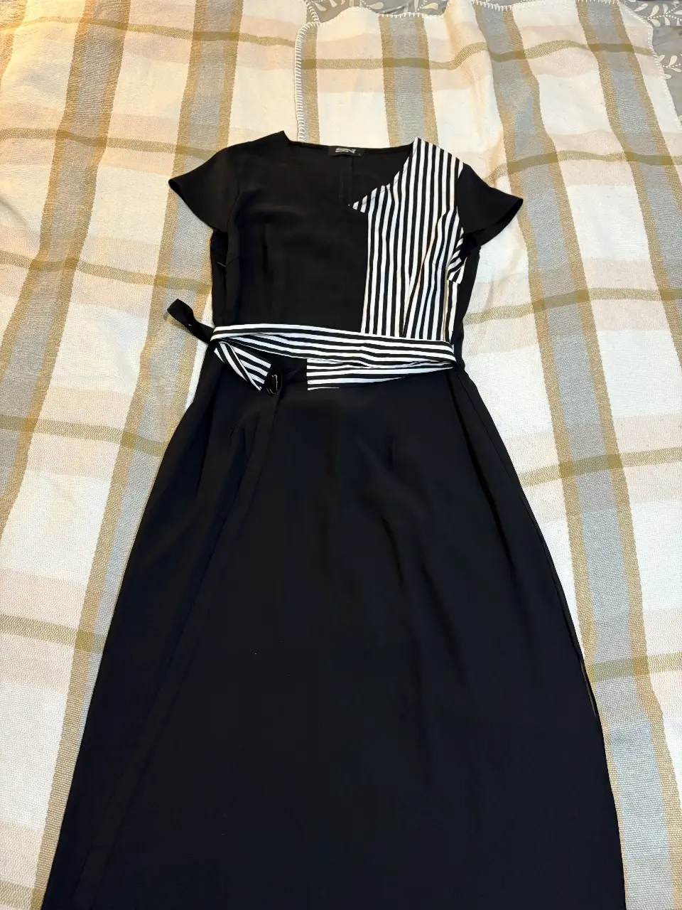 Vestido midi negro con detalle en blanco y negro en la parte superior. Cinturón a juego para ajustar la cintura. Ideal para eventos formales o salidas.
