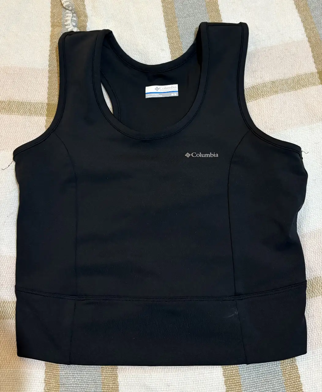 Top deportivo Columbia negro, ideal para entrenamientos. Diseño con espalda cruzada y logo de la marca.
