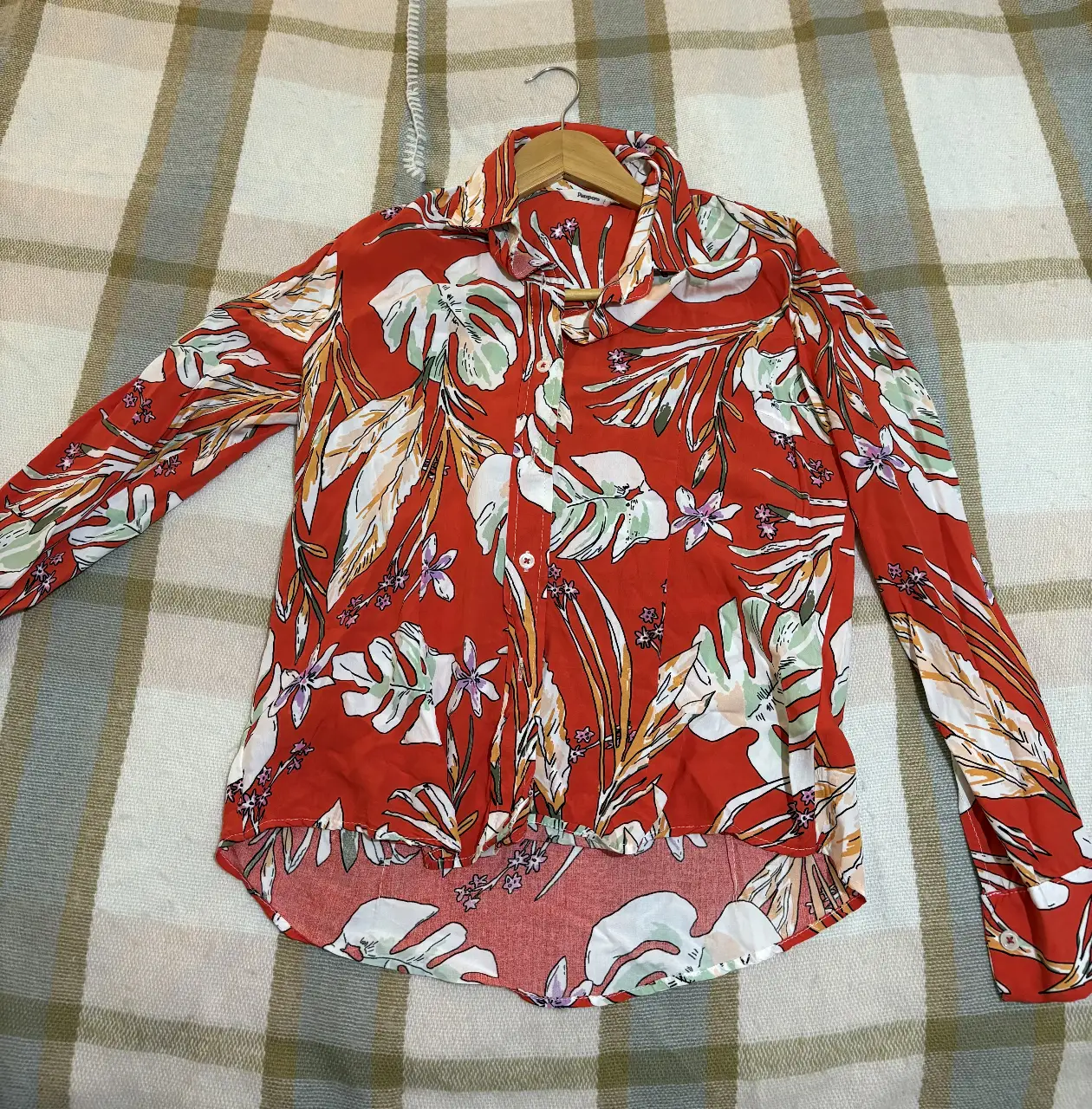 Camisa estampada con diseño floral en tonos rojos, blancos y detalles en verde y amarillo. Ideal para un look casual y fresco.