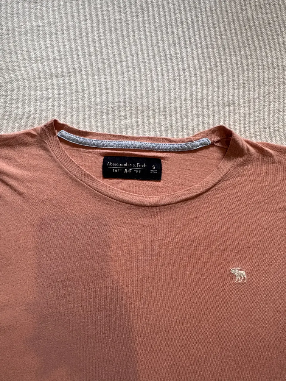 Remera de manga corta Abercrombie & Fitch color rosa, con el logo de la marca bordado en el pecho. Talle S.