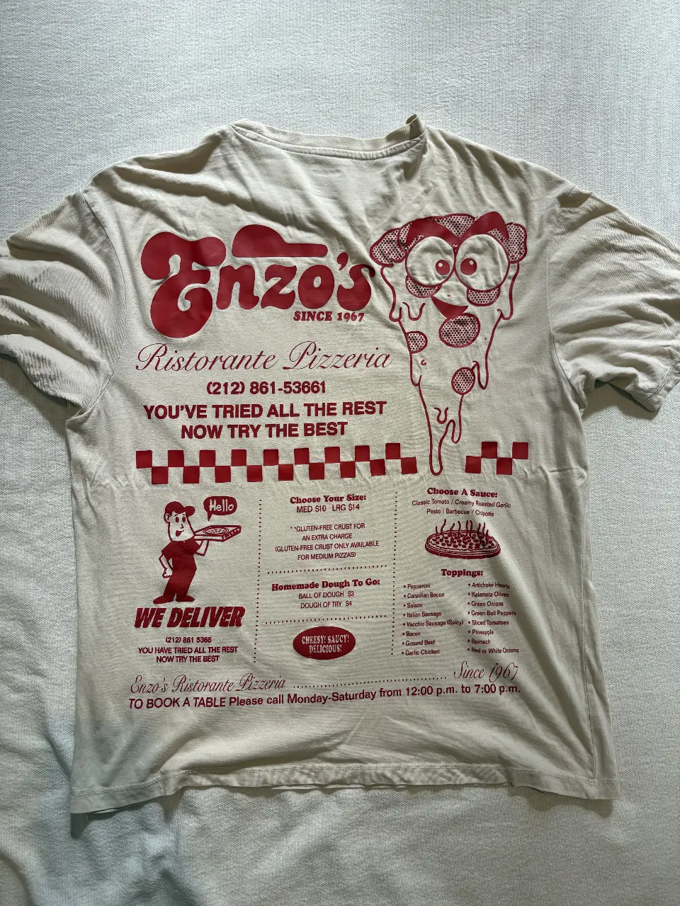 Remera de algodón color crudo con estampado de Enzo's Ristorante Pizzeria en la parte delantera y trasera. Diseño vintage con detalles en rojo. Ideal para un look casual y retro.