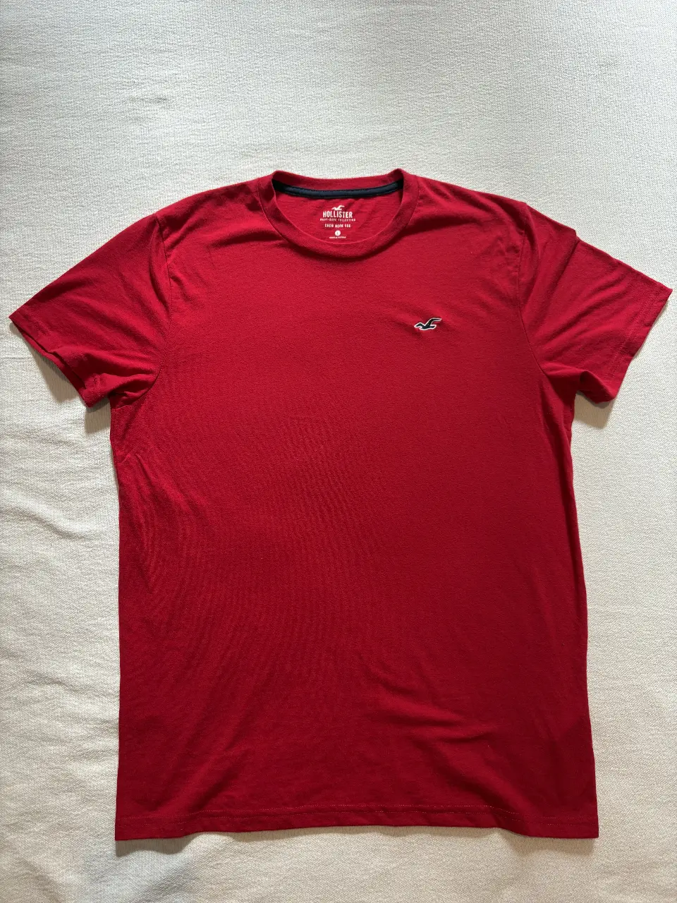 Remera roja de hombre, manga corta, con logo de la marca Hollister en el pecho. Ideal para un look casual y cómodo.