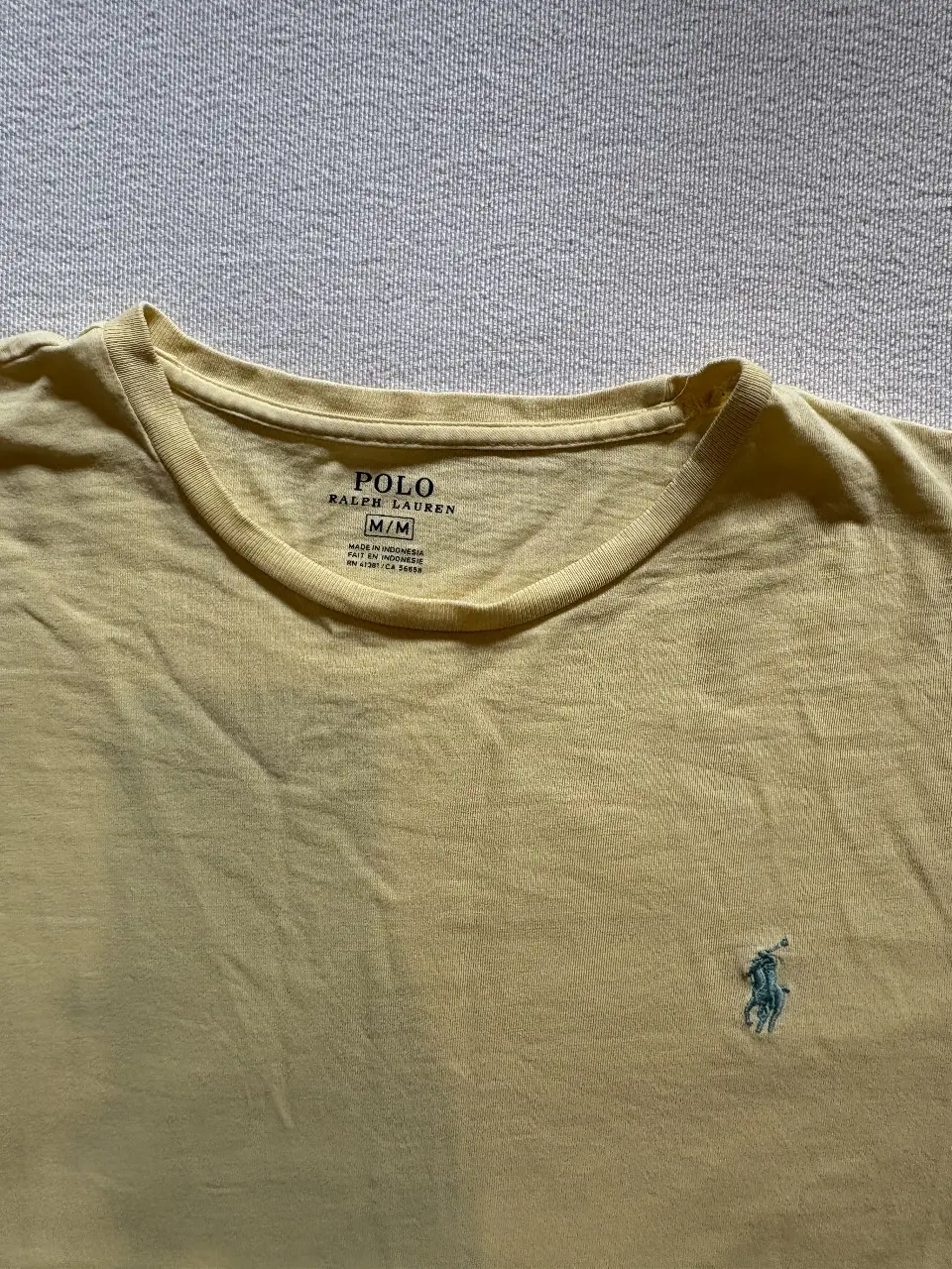 Remera Polo Ralph Lauren amarilla, manga corta, con el logo del jugador de polo bordado en celeste. Ideal para un look casual y cómodo.