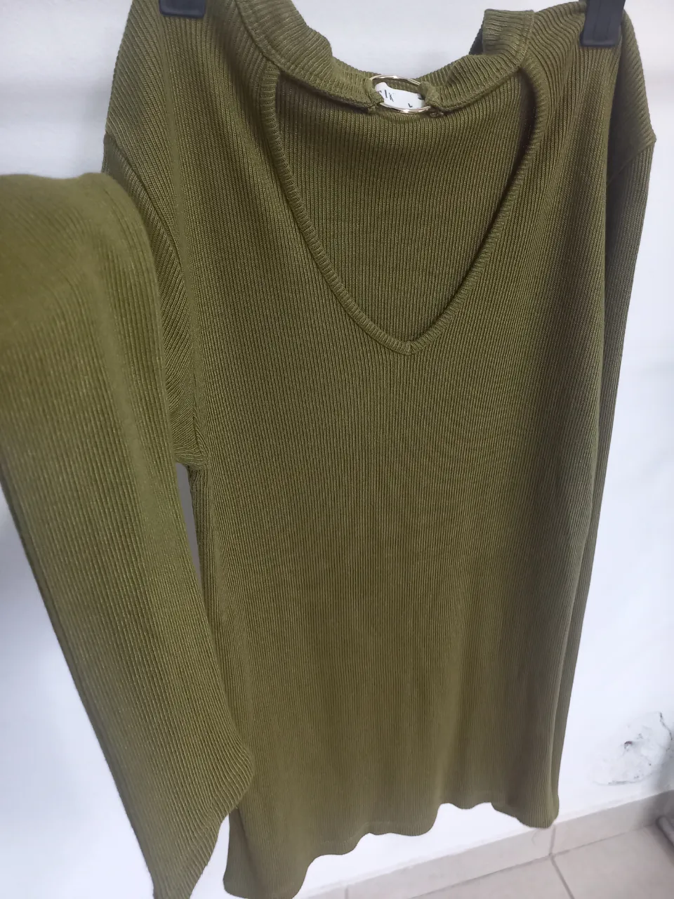 Sweater de punto con cuello en V y detalle de aro metálico. Ideal para un look casual y moderno.