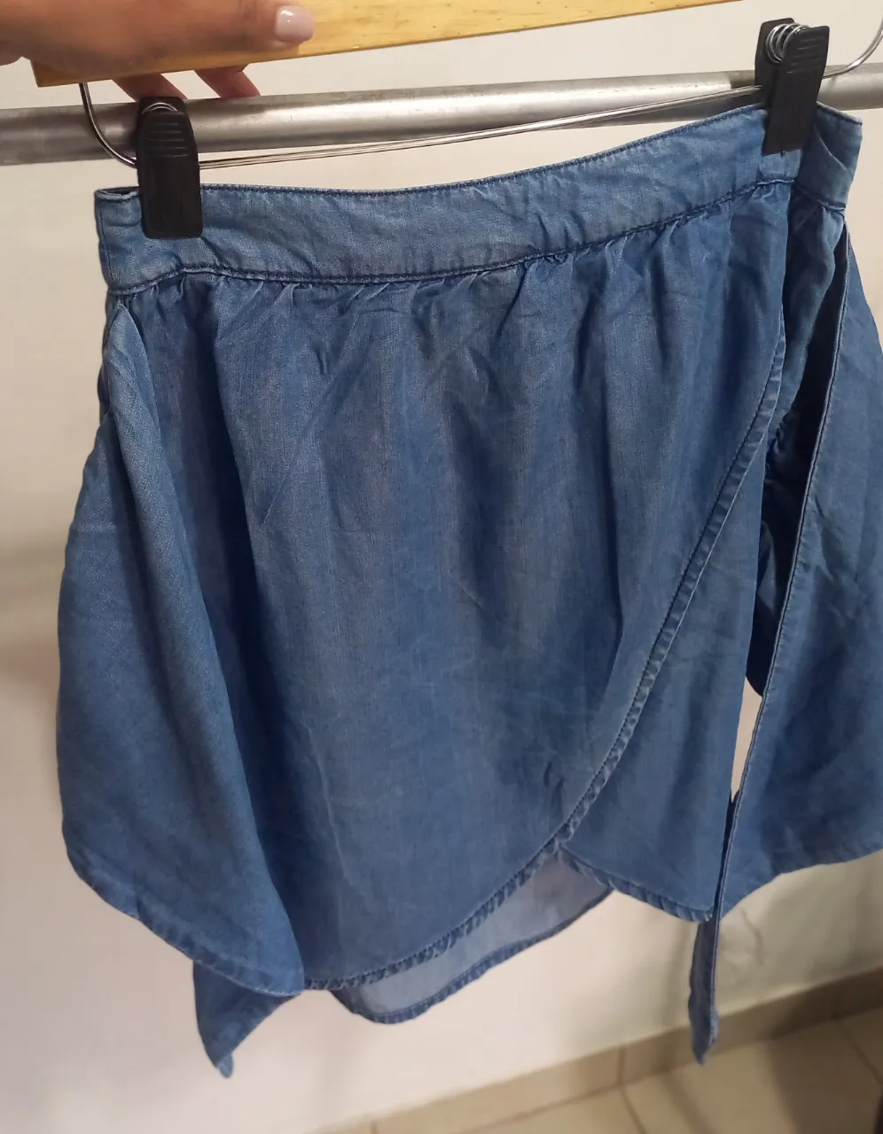 Pollera asimétrica de jean azul, con detalle de lazo en la cintura. Ideal para un look casual y moderno.