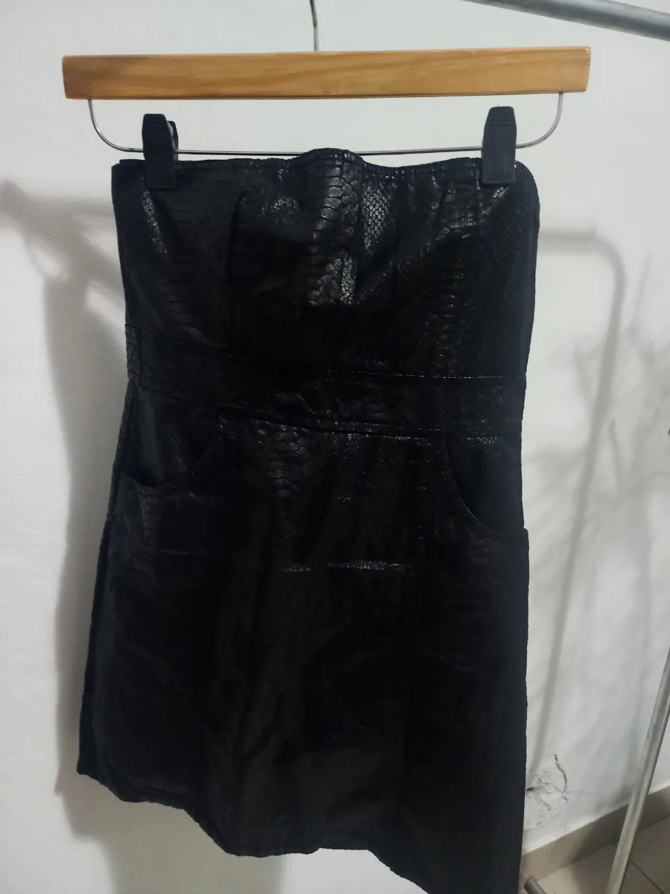 Vestido mini strapless negro con textura símil piel de serpiente, con bolsillos y cierre en la espalda. Talle 34.