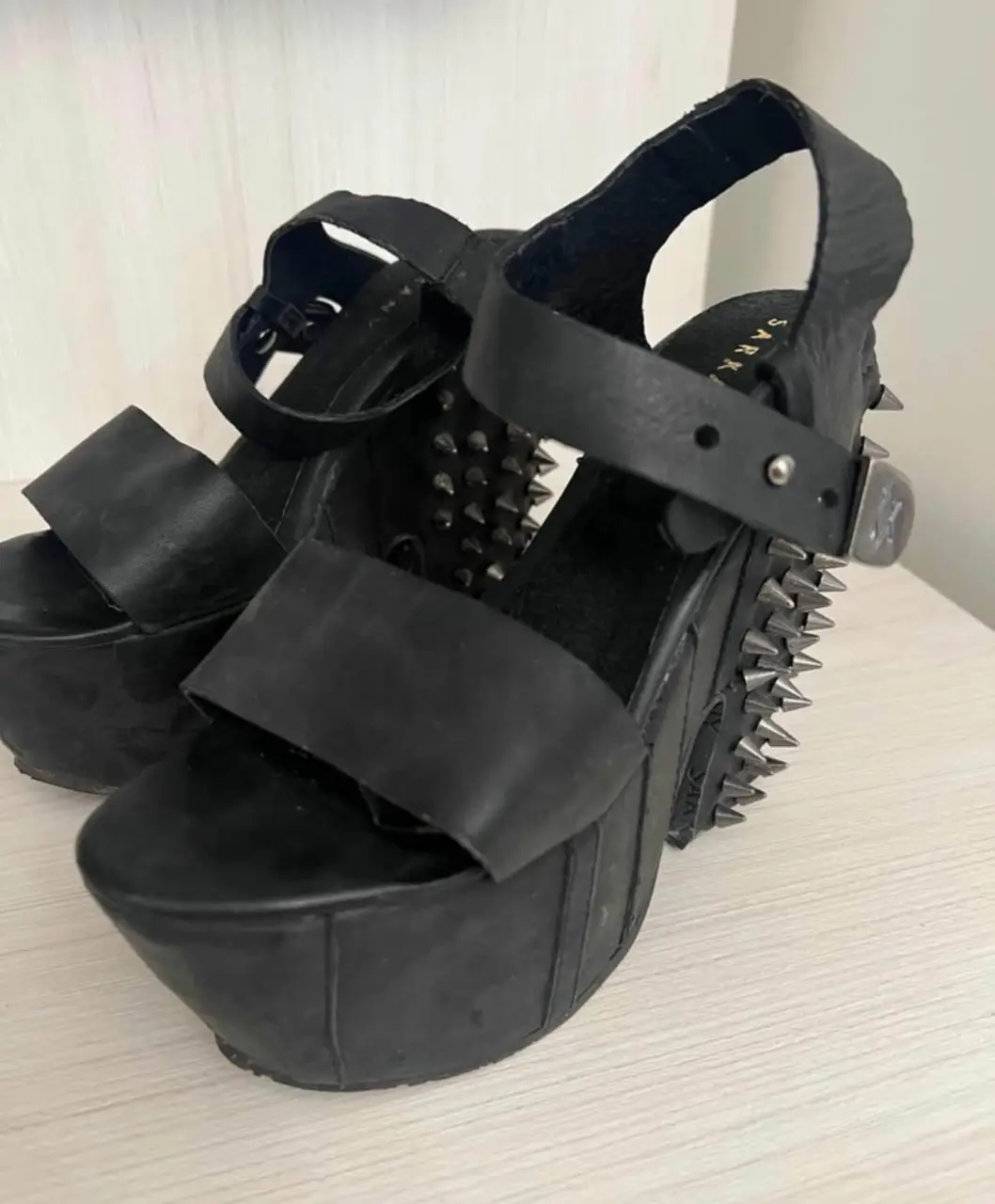 Sandalias de plataforma negras con detalles de tachas metálicas. Diseño audaz y moderno, ideales para un look rockero y llamativo.