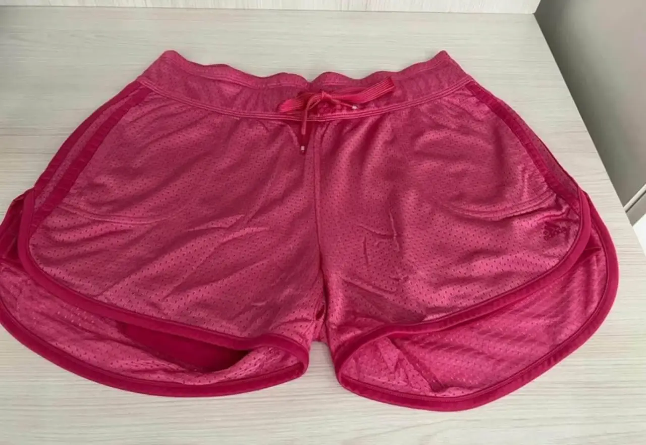Short deportivo Adidas rosa para mujer. Ideal para running y entrenamientos. Confeccionado en poliéster y algodón, con cintura elastizada y cordón ajustable. Detalles de diseño Adidas.
