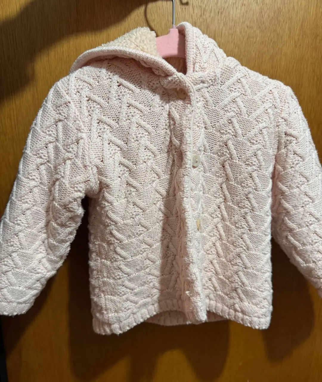Cárdigan tejido para niña, color rosa claro, con capucha y botones. Ideal para abrigar a tu pequeña con estilo y comodidad.