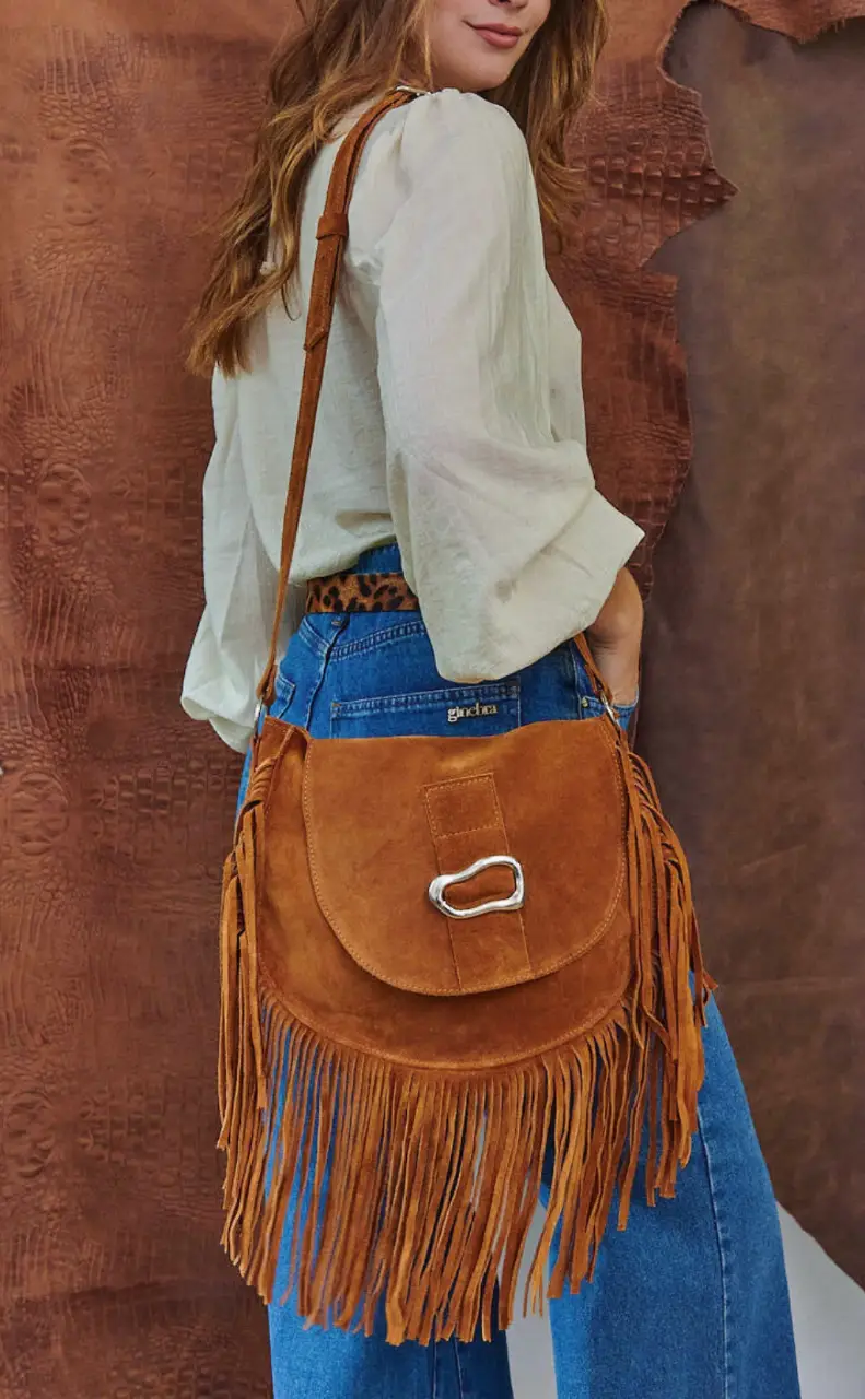 Cartera bandolera de gamuza marrón con flecos. Diseño boho con hebilla plateada y correa ajustable. Ideal para un look casual y con estilo.