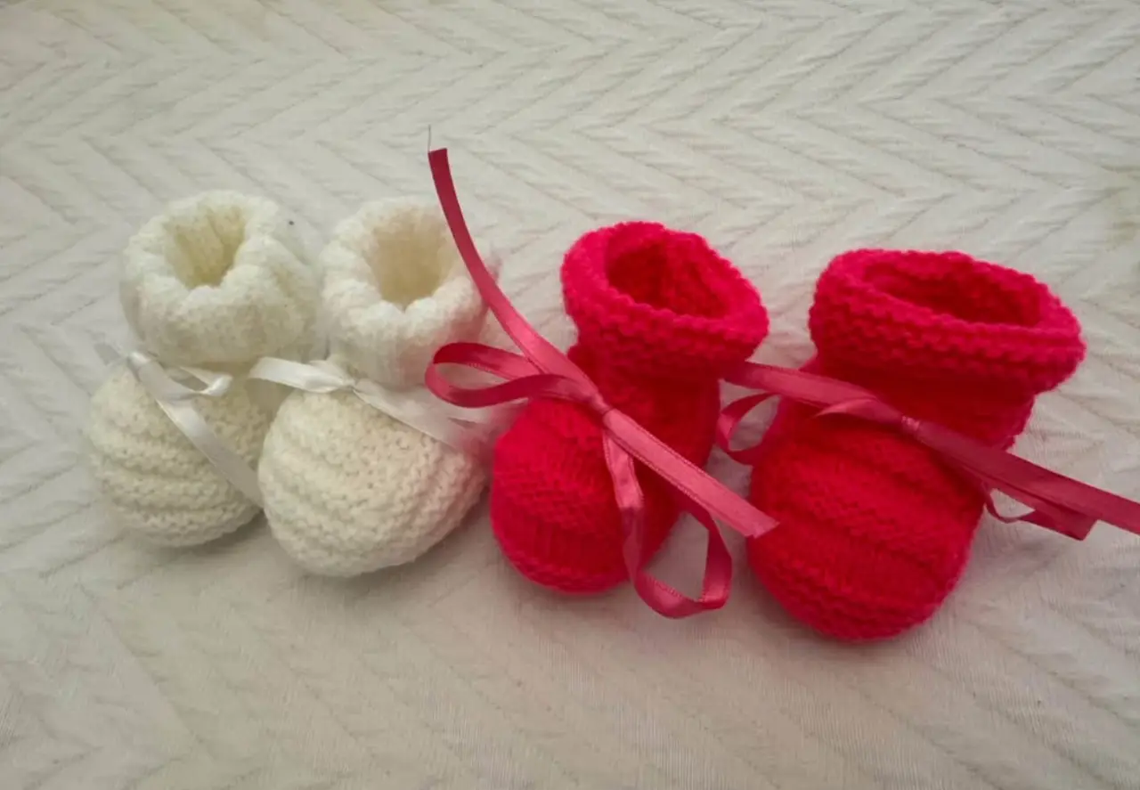 Lindos escarpines tejidos a mano para bebé, en color blanco y rojo, con cintas de raso para atar. Ideales para regalo o para mantener los pies de tu bebé abrigados y con estilo.